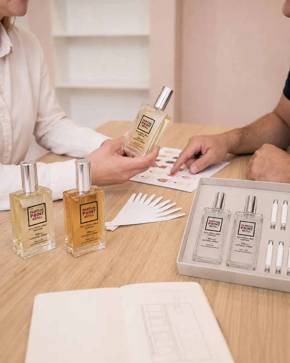 Winkelier en adviseur van ParfumPoint Refill bekijken samen parfumflesjes en geurstrips aan een tafel